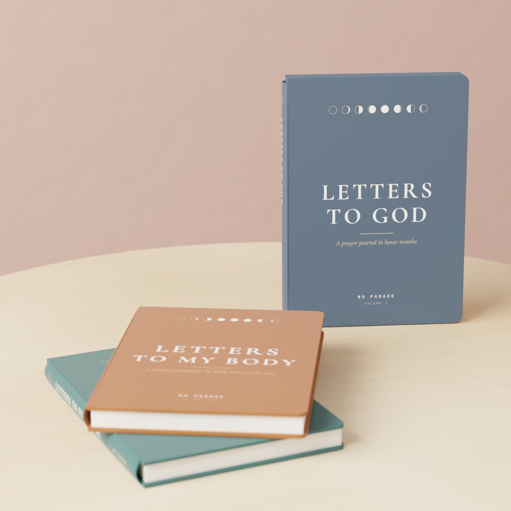 The three Letters to God journals by NO PARADE on an oak stool: Volume I standing, Volumes II and III stacked